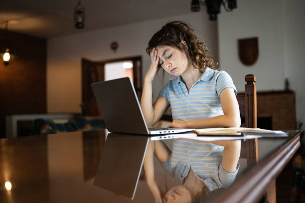 istock Tired young woman using laptop at home 1341429631