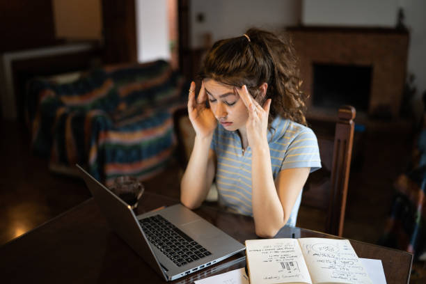 istock Tired young woman using laptop at home 1341429635