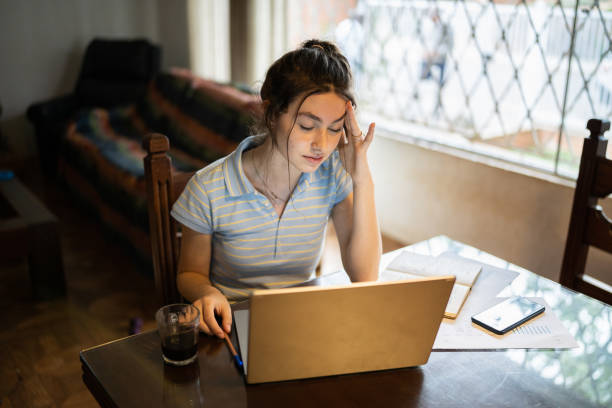 istock Tired young woman using laptop at home 1341429640