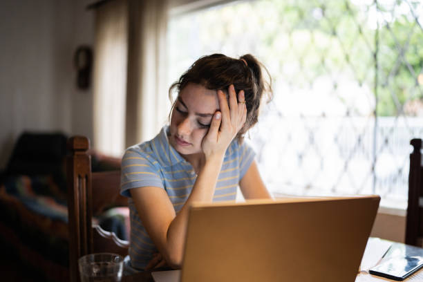 istock Tired young woman using laptop at home 1341429646