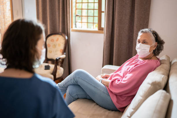 istock Nurse talking with a senior patient at home - wearing a face mask 1341430434
