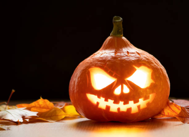 istock Festive scary halloween pumpkin on leaves on dark background 1341434677