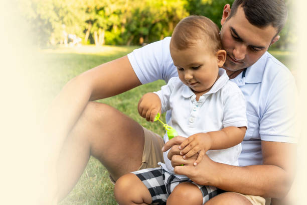 istock cute little boy with single father blows soap bubbles in park and have fun 1341435584