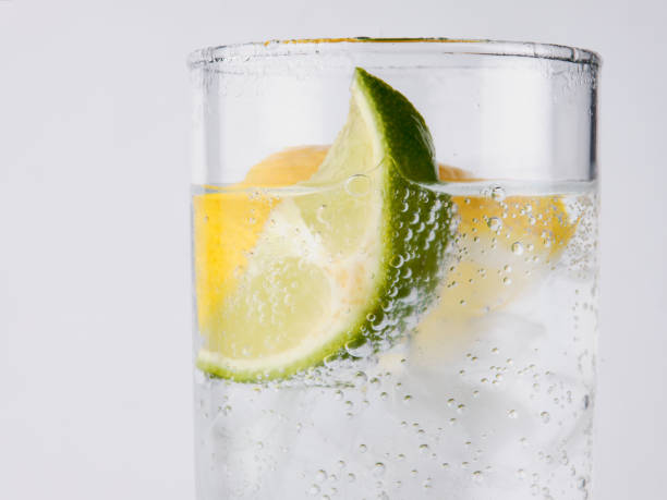 agua de soda, lima y limón salpicando en un vaso de agua fondo blanco - water flowing water pouring ice fotografías e imágenes de stock