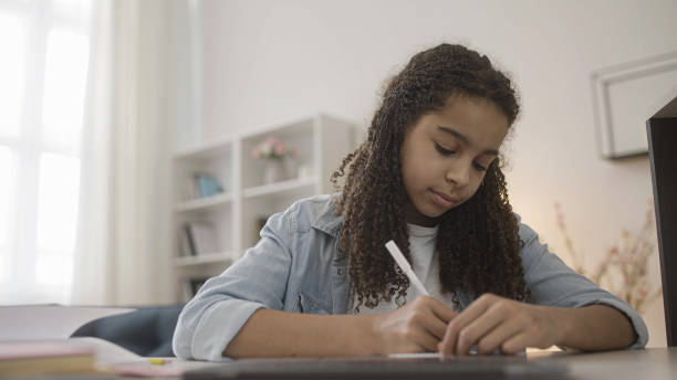 istock Teenage girl doing homework on laptop, making notes, distance learning 1341439150