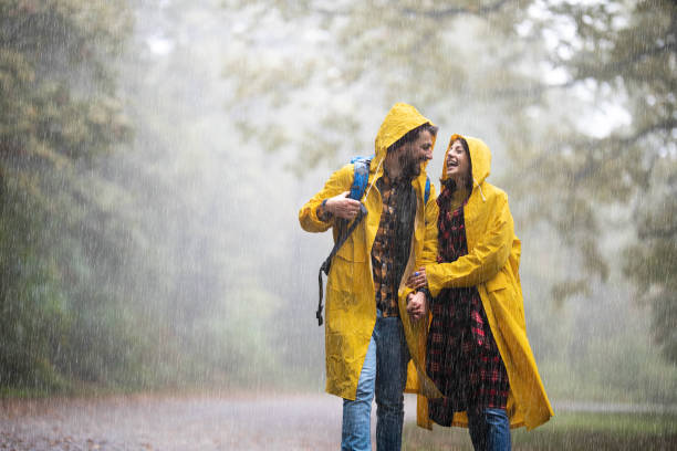istock Happy couple in raincoats talking while walking in misty forest. 1341439310