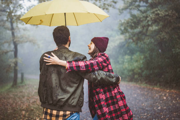 istock Happy embraced couple walking under umbrella on a rainy day. 1341439340