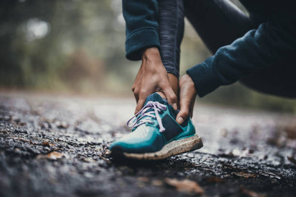 primer plano de una atleta irreconocible sosteniendo su tobillo con dolor en el parque. - ankle fotografías e imágenes de stock