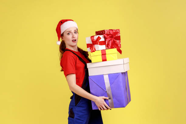 donna di consegna confusa che tiene una pila di regali e guarda la telecamera con espressione che chiede. - christmas stack gift carrying foto e immagini stock