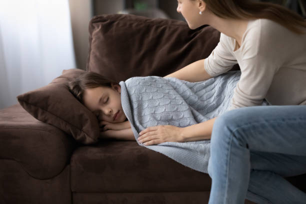 istock Caring young mother covering sleepy small daughter. 1341442177