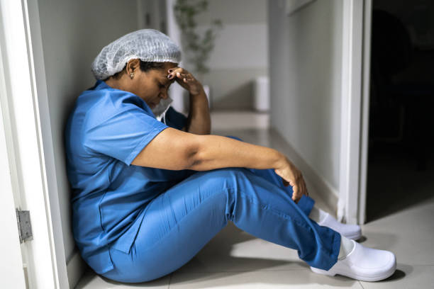 уставший / обеспокоенный медицинский работник в больнице - doctor tired protective workwear sadness стоковые фото и изображения