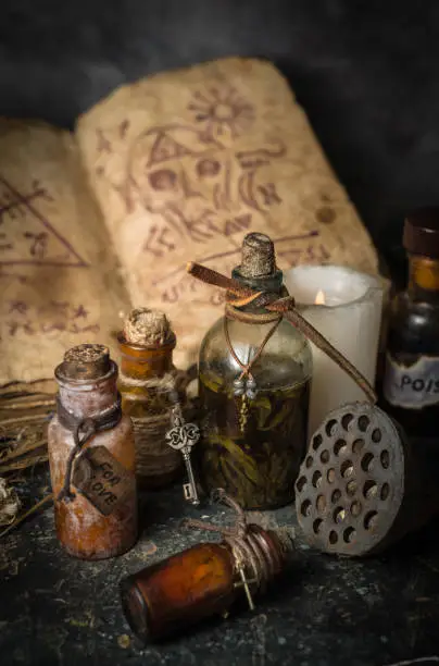 Magic potions in bottles, ancient books and witchery herbs on wooden background