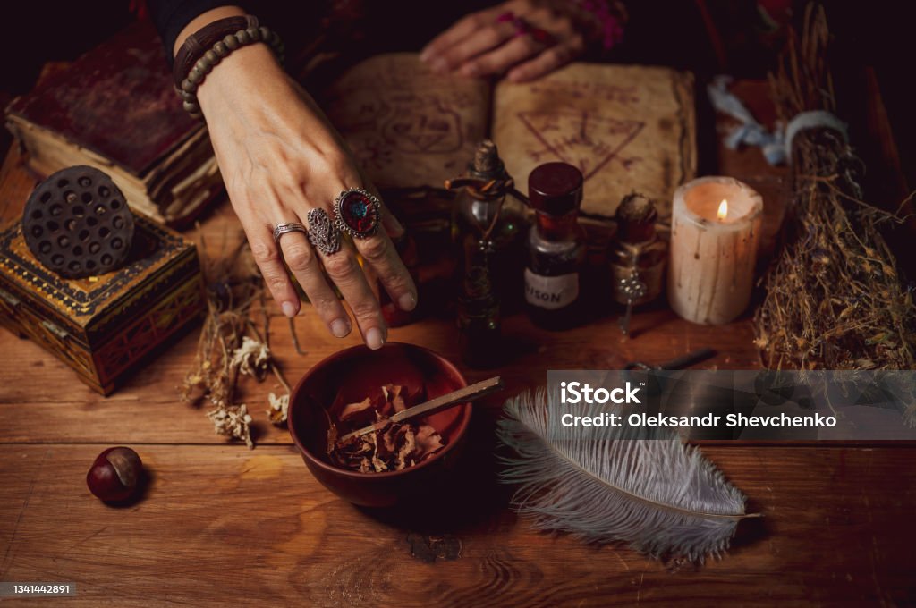 Female witch making potion on dark background, magic bottles with potions and candles on table of alchemist, Halloween theme Female witch making potion on dark background Witch Stock Photo