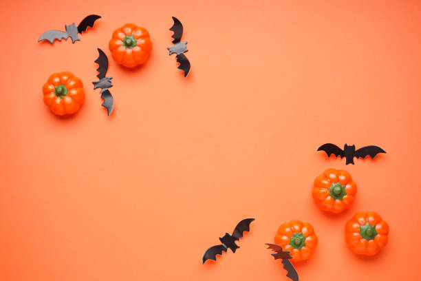 istock Halloween pumpkins and bats on orange background, space for text, flat lay. Halloween concept. 1341443167