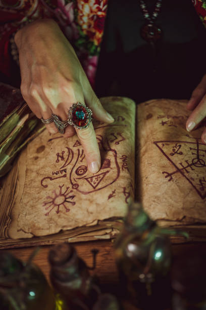 istock Female witch making potion on dark background, magic bottles with potions and candles on table of alchemist, Halloween theme 1341443742