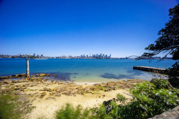 istock Sunny Spring day on Sydney Harbour with nice rocks in the foreground the soft waves crashing on the shore and the beautiful harbour foreshore as a backdrop NSW Australia 1341446028