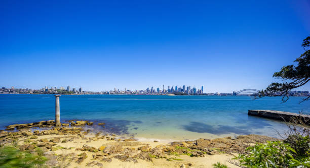 istock Sunny Spring day on Sydney Harbour with nice rocks in the foreground the soft waves crashing on the shore and the beautiful harbour foreshore as a backdrop NSW Australia 1341446087