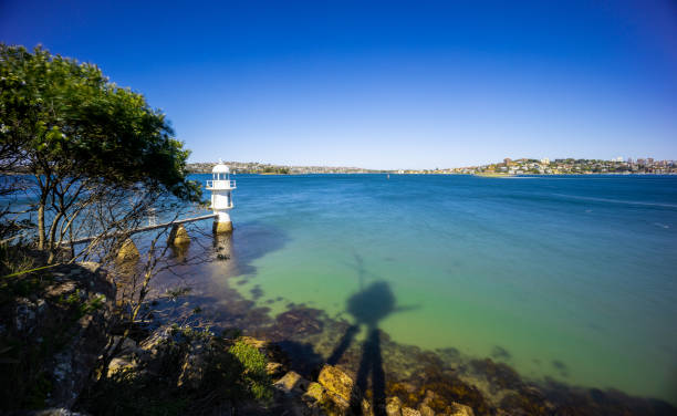 Sunny Spring day on Sydney Harbour with nice rocks in the foreground the soft waves crashing on the shore and the beautiful harbour foreshore as a backdrop NSW Australia