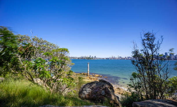 istock Sunny Spring day on Sydney Harbour with nice rocks in the foreground the soft waves crashing on the shore and the beautiful harbour foreshore as a backdrop NSW Australia 1341446158