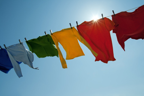 Sun shining over a laundry line with bright clothes on a windy day.