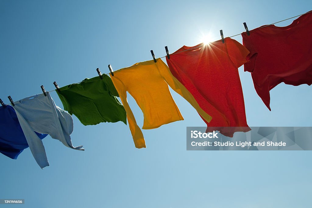 Sun shining over a laundry line with bright clothes Sun shining over a laundry line with bright clothes on a windy day. Clothing Stock Photo