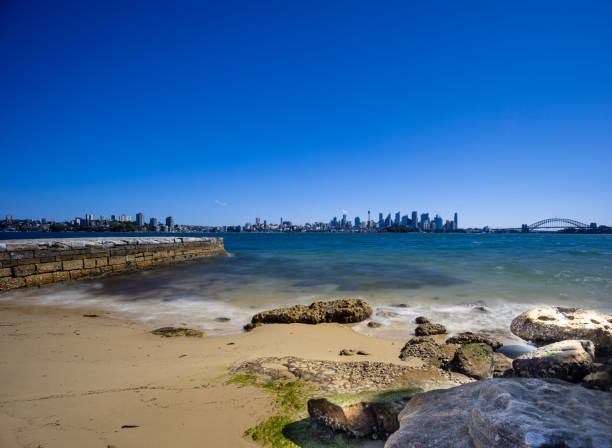 istock Sunny Spring day on Sydney Harbour with nice rocks in the foreground the soft waves crashing on the shore and the beautiful harbour foreshore as a backdrop NSW Australia 1341446576