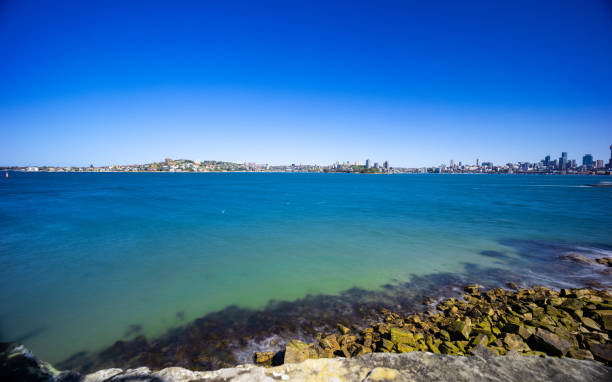istock Sunny Spring day on Sydney Harbour with nice rocks in the foreground the soft waves crashing on the shore and the beautiful harbour foreshore as a backdrop NSW Australia 1341447334