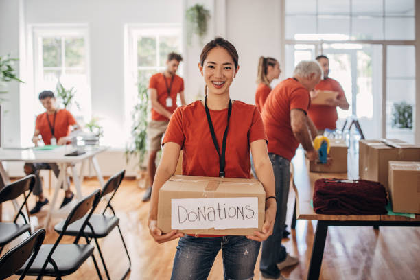 retrato de un voluntario sosteniendo una caja de donación con productos para personas necesitadas - caridad y auxilio fotografías e imágenes de stock