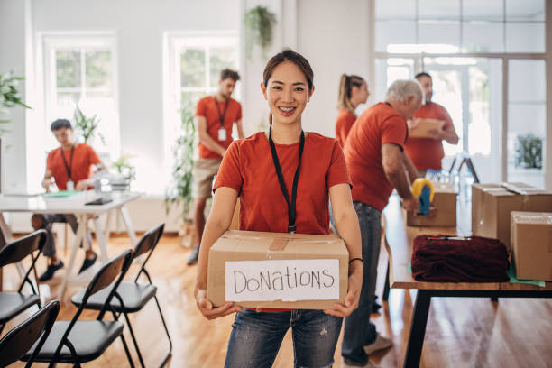 Portrait of volunteer holding donation box with goods for people in need Portrait of volunteer holding donation box with goods for people in need charitable foundation stock pictures, royalty-free photos & images