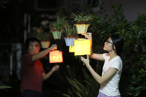 An Asian couple are enjoying decorating garden with lanterns.