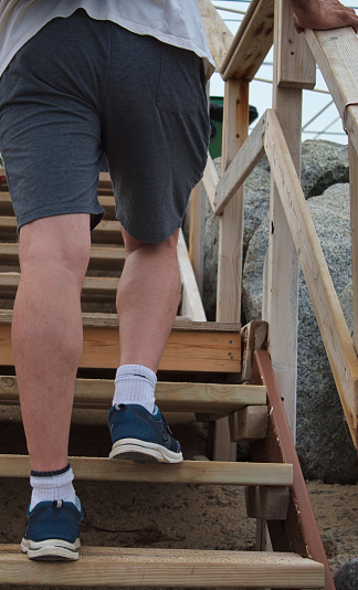 vista desde detrás de un pie de un hombre subiendo una escalera de madera cerca de la playa de Vilassar de Mar, España photo