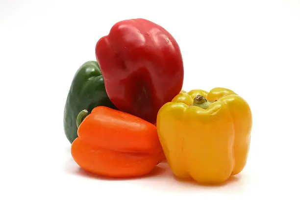 Red, Yellow, Green and Orange Bell Peppers against a white background