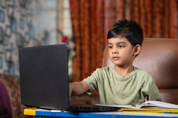 kleiner junge, der den online-schulunterricht mit laptop zu hause besucht. - reading and writing little boys reading asian ethnicity stock-fotos und bilder
