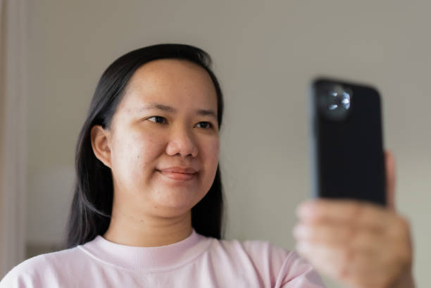 istock Asian woman using mobile phone for video calling with her smile 1341456363