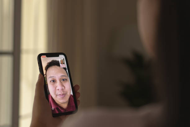 istock Focusing at hand with phone while a woman using video calling with husband 1341456886