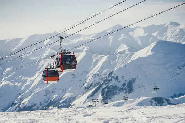 two large ski lifts in the sunny mountains transport people