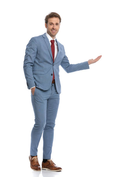 istock smiling young man in blue suit presenting to side and walking 1341458317