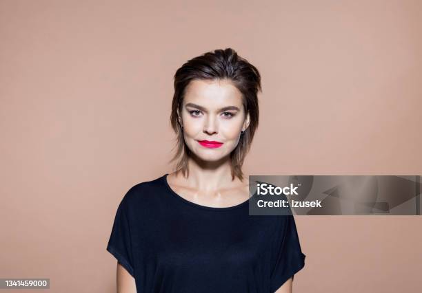Businesswoman Standing Against Brown Background Stock Photo - Download Image Now - Design Professional, Portrait, Headshot