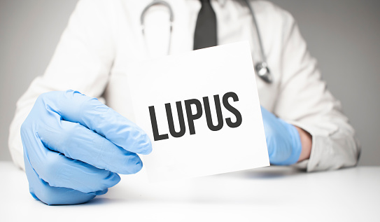 White sticker with text Lupus in doctor's hands with a stethoscope