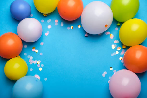 istock Colorful balloons and confetti on blue table top view 1341459997