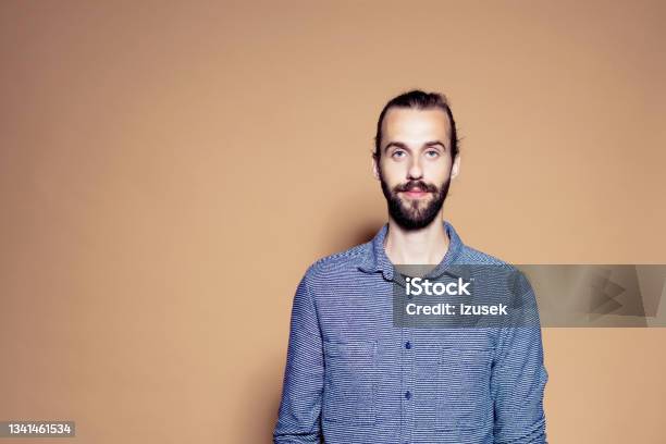 Portrait Of Confident Bearded Man Stock Photo - Download Image Now - Brown Background, Males, 25-29 Years