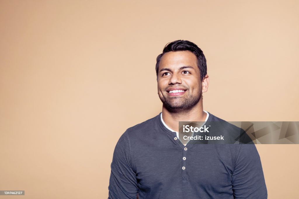 Smiling man over brown colored background Headshot of smiling entrepreneur looking away. Confident mid adult man standing against brown background. 30-39 Years Stock Photo