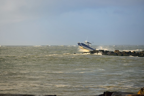 A catamaran leaping over waves in the Ocean City, MD inlet in a high risk environment