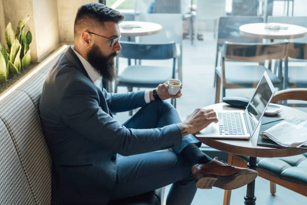 istock Serious Businessman Drinking Espresso and Working on Laptop Computer in a Cafe 1341463748