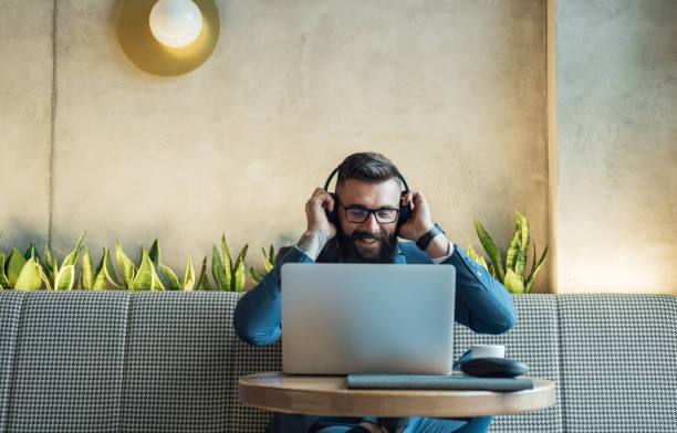 apuesto hombre de negocios que pone auriculares inalámbricos antes de una reunión en línea en un café - restaurant wireless technology office worker business fotografías e imágenes de stock