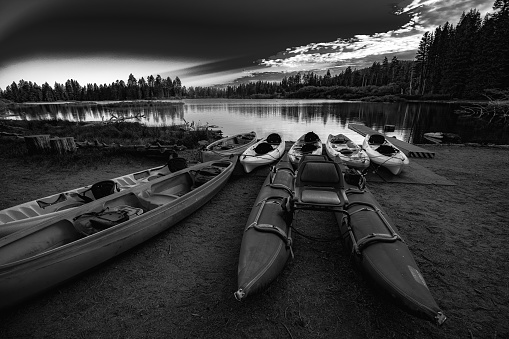 Kayaks sit idle on a lake in the morning sunrise.