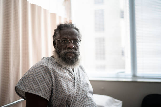 portret starszego pacjenta siedzącego na szpitalnym łóżku - examination gown zdjęcia i obrazy z banku zdjęć