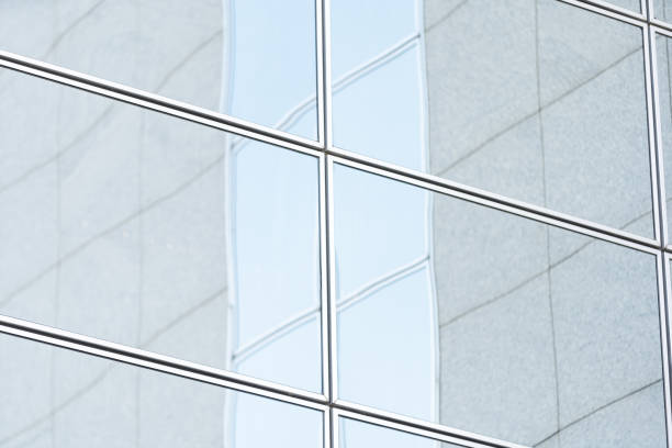 istock Perspective and underside angle view to textured background of modern glass building skyscrapers over blue cloudy sky 1341469436