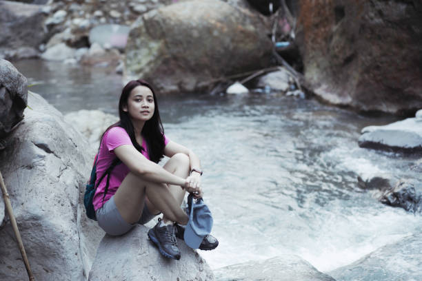 istock woman, with backpack walking on rocks to cross a river during a summer day 1341469511