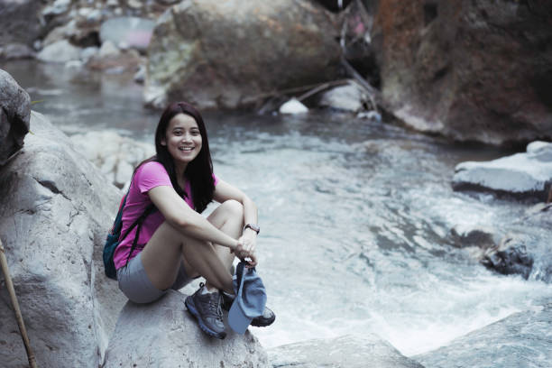 istock woman, with backpack walking on rocks to cross a river during a summer day 1341469514